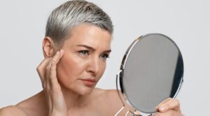 Skin Aging. Mature woman looking in the mirror checking her wrinkles